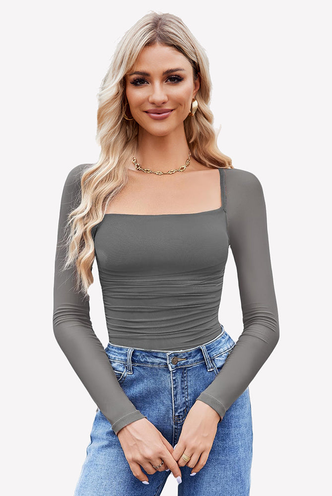 Grey square neck mesh bodysuit with long sleeves, ruched detail. Model in jeans and gold jewelry.
