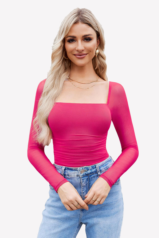 Pink square neck mesh bodysuit with ruched detail and long sleeves. Model in jeans and gold jewelry.