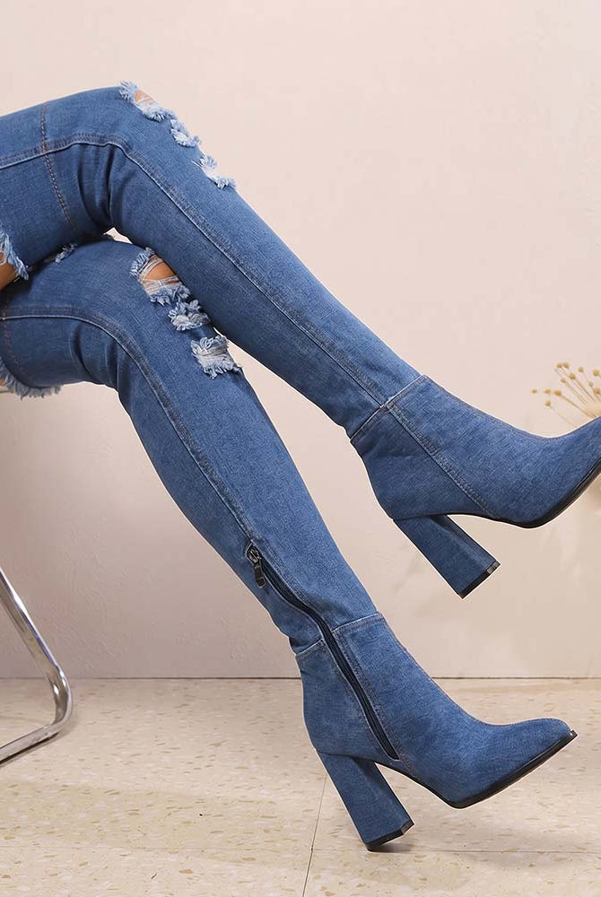 Distressed over-the-knee stiletto boots in blue denim, pointed toe, tall block heel, side zip.