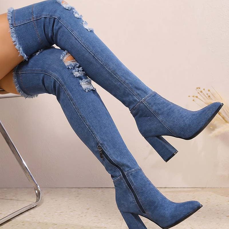 Distressed over-the-knee stiletto boots in blue denim, pointed toe, tall block heel, side zip.