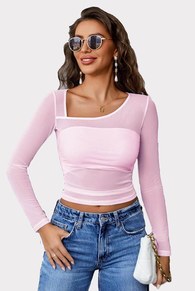 Pink mesh asymmetrical crop top with long sleeves, unique neckline, and denim jeans.