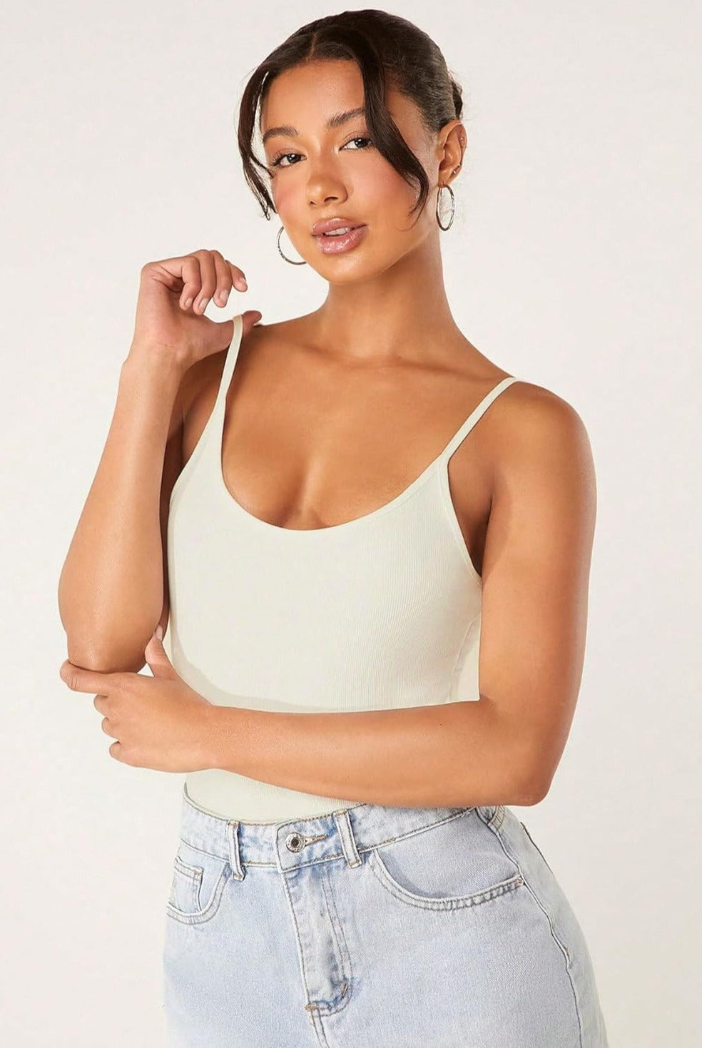 Beige ribbed tummy control romper with thin straps and scoop neck, hand at shoulder strap