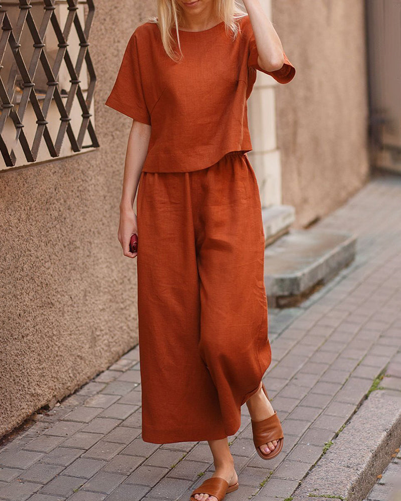 Orange linen two-piece set, casual style. Loose fit top and wide leg pants for leisure wear.