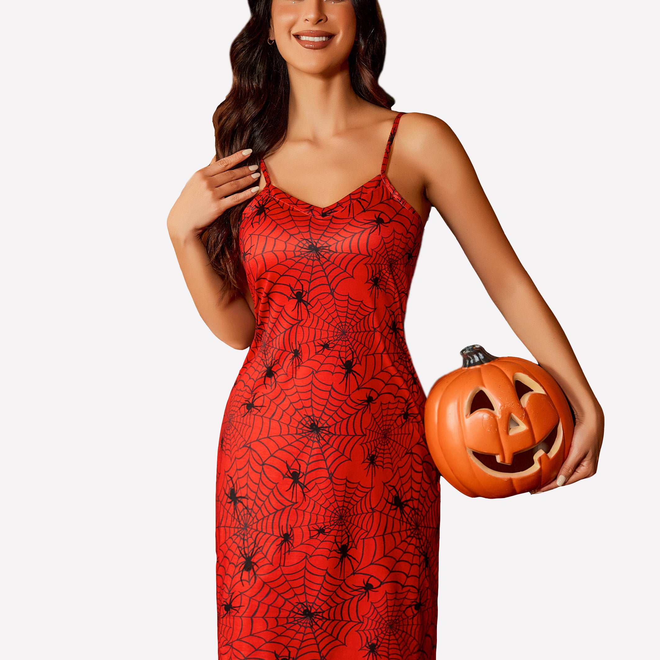 Red spiderweb print chemise dress with spaghetti straps, woman holding jack-o'-lantern