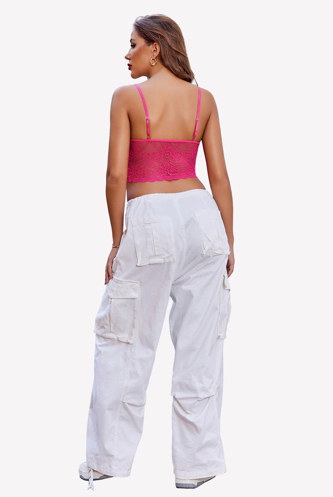 Back view of a woman in pink lace bralette and white cargo pants. Elegant lingerie set.