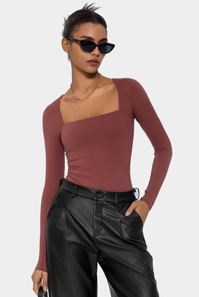 Terracotta square neck bodysuit, long sleeve, elegant shapewear. Paired with black leather pants.