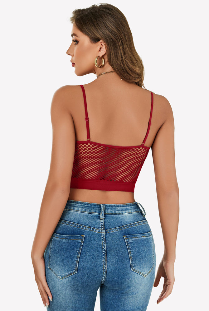 Red fishnet crop top Y2k bralette, mesh detail, paired with blue jeans, showing curves.
