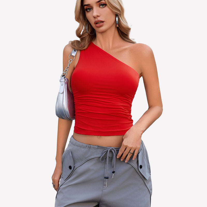 Red one-shoulder crop top with ruched detail, gray cargo pants. Stylish outfit.
