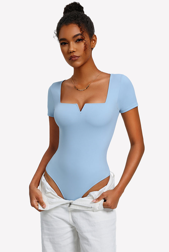 Light blue square-neck short-sleeve bodysuit on model with open-back hip strap detail