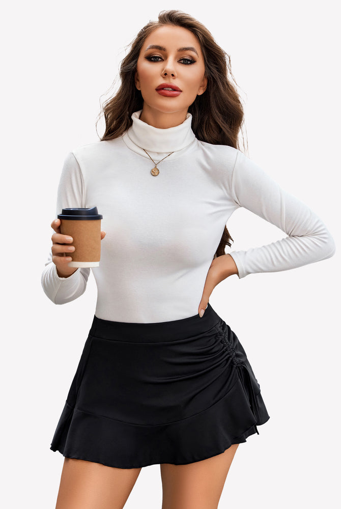 Stylish woman in black pleated mini skirt, white turtleneck, wrap front design for confident women.