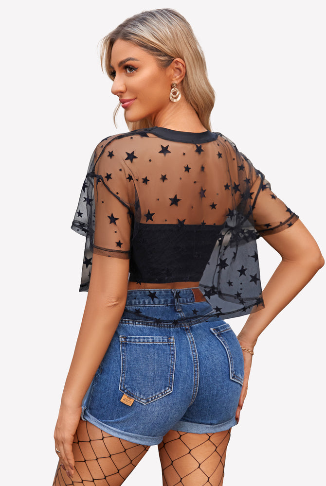 Black mesh crop top with stars, denim shorts, and fishnet stockings. Trendy see-through mesh shirt.