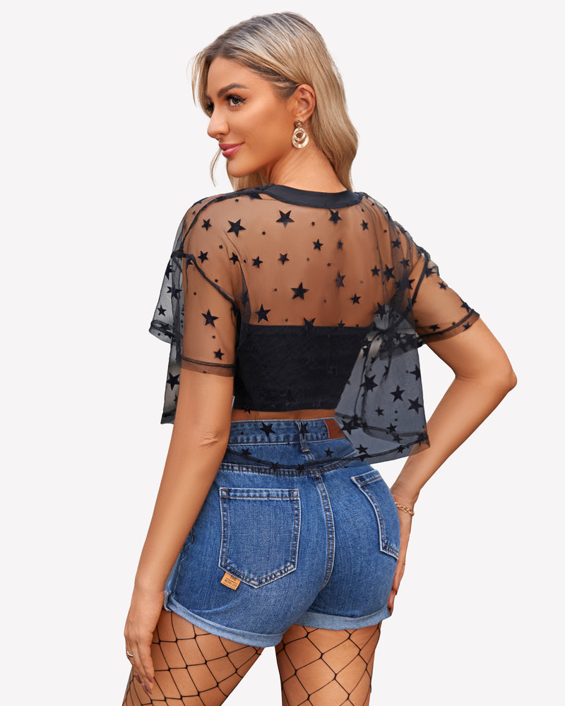 Black mesh crop top with stars, denim shorts, and fishnet stockings. Trendy see-through mesh shirt.