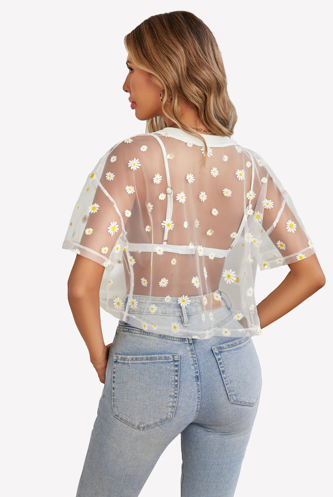 White daisy mesh crop top paired with light blue jeans, trendy see-through shirt.