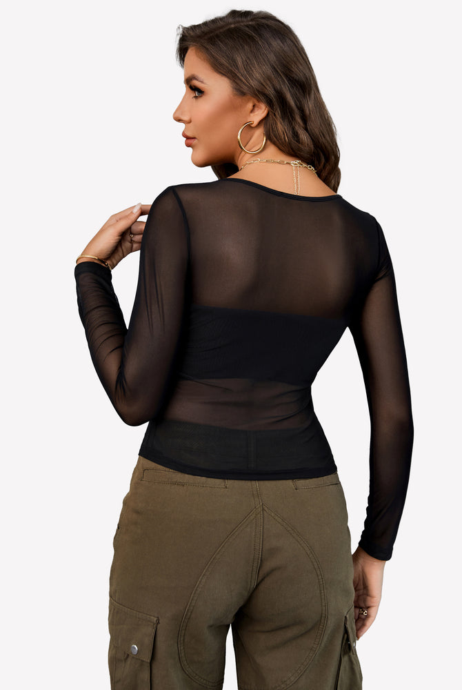Black sheer mesh crop top with asymmetrical neckline and long sleeves paired with olive cargo pants.
