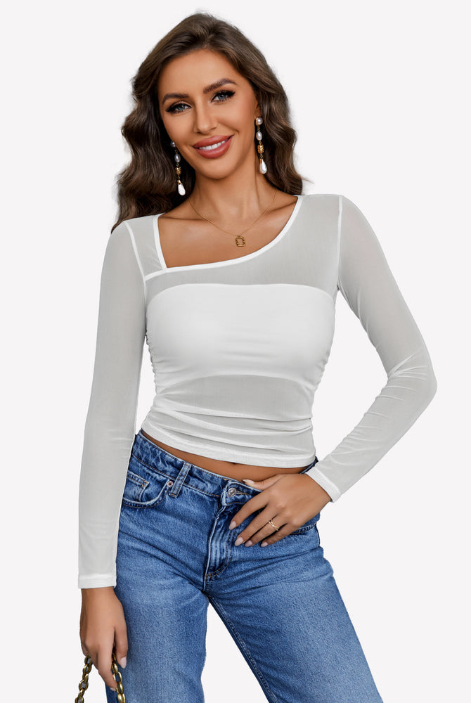 White asymmetrical mesh crop top, long sleeve, paired with denim jeans. Stylish, sheer top.