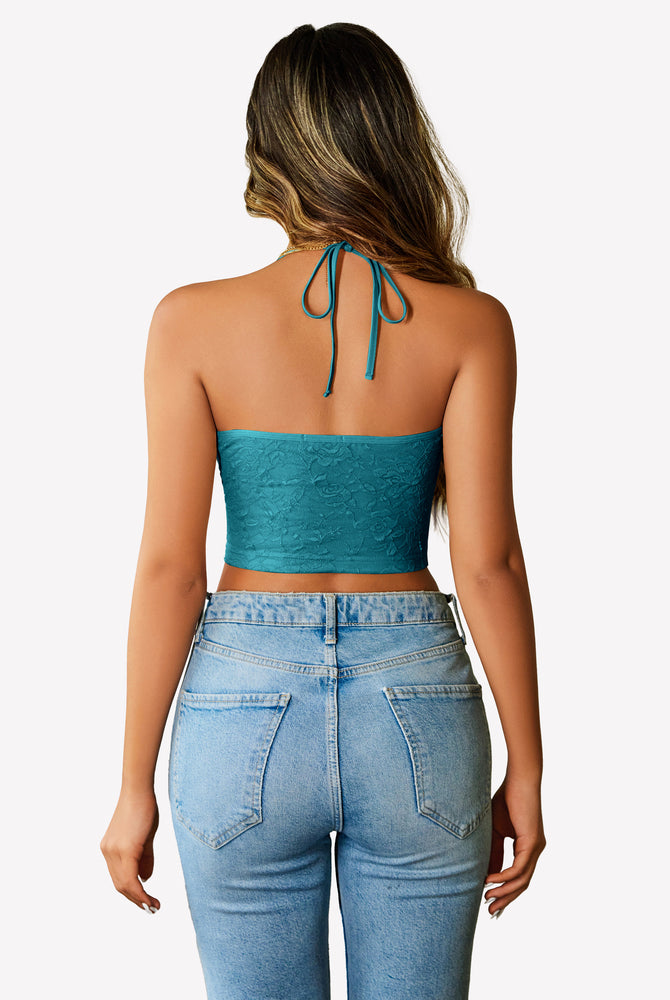 Teal lace halter crop top with adjustable straps and light wash jeans. Y2k style.