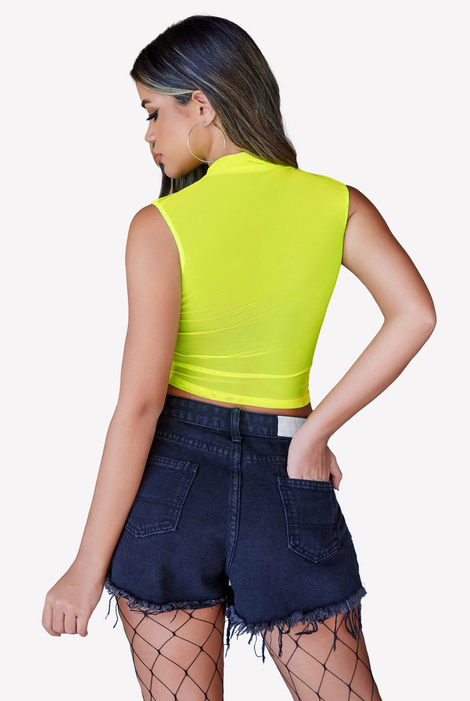 Neon green mesh mock neck top with black denim shorts, a stylish and confident look.