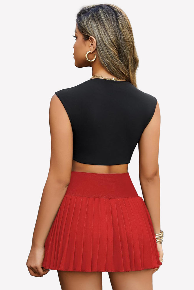 Red pleated mini skirt with black crop top. High-waisted design, perfect for confident style.