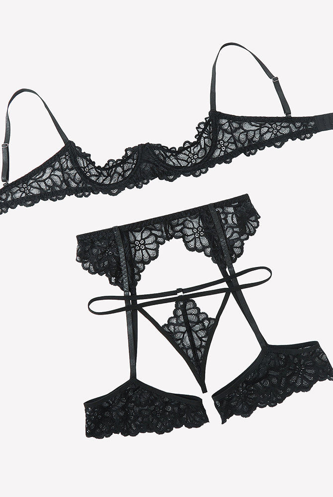 Black lace lingerie set flat lay: lace bra top, thong, garter belt, and thigh straps