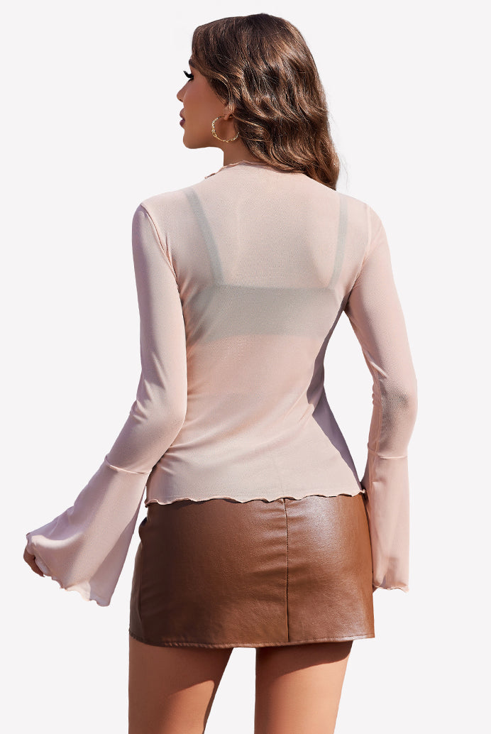 Nude mesh top with bell sleeves and brown leather skirt, a stylish and confident look.