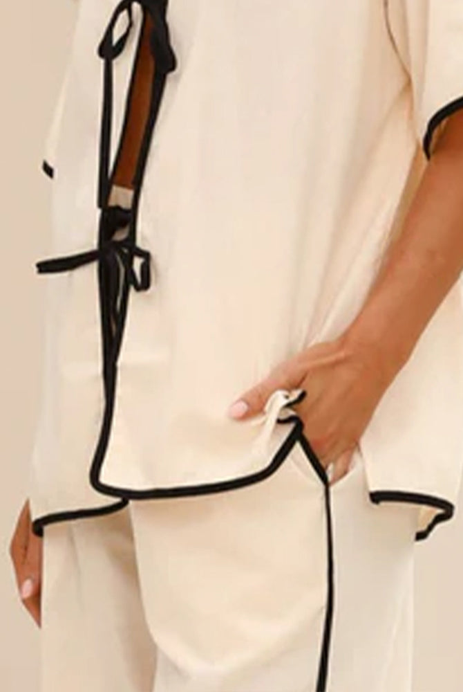 Beige linen pajama shirt front with lace-up ties and black trim detail.