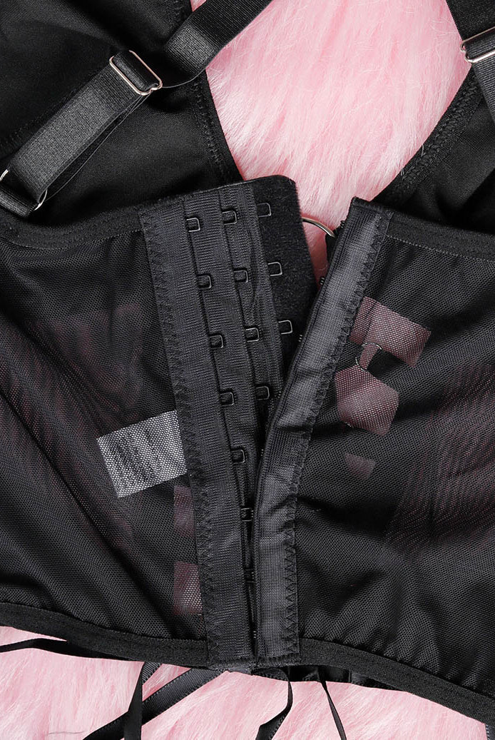 Close-up of black bra back with adjustable hook-and-eye band and sheer mesh panels