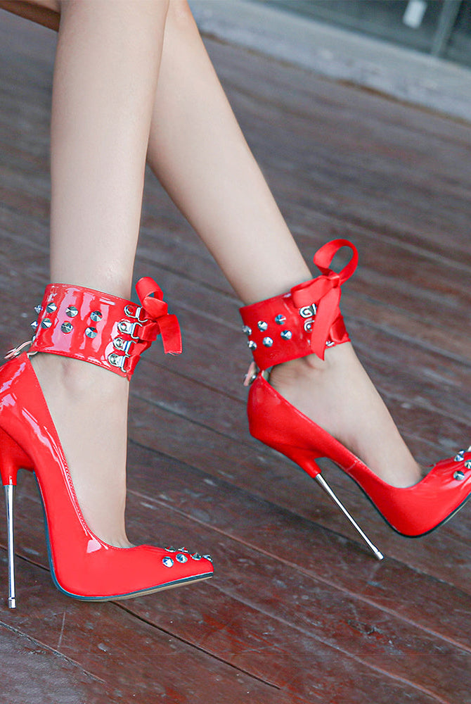 Red pointed-toe stiletto heels with studded ankle strap and lace-up ribbon bow
