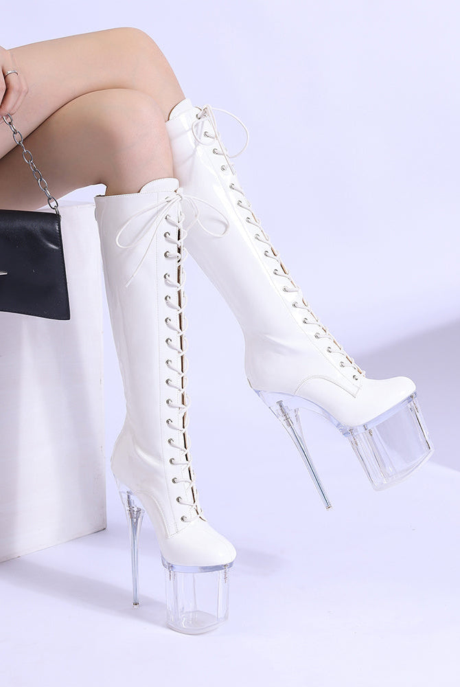 White knee-high lace-up patent stiletto boots with clear platform heel, angled view