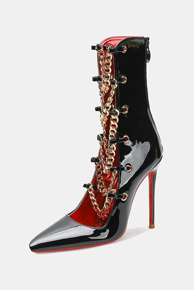 Black patent stiletto ankle boot with gold chain detail and contrast red lining.