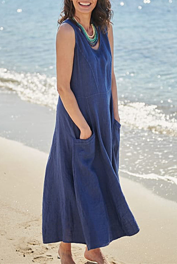 Sleeveless blue linen dress with pockets, perfect for vacation, on a woman at the beach