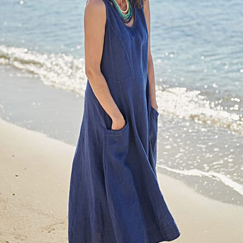 Sleeveless blue linen dress with pockets, perfect for vacation, on a woman at the beach