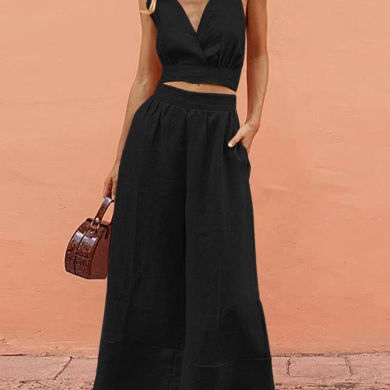 Black crop top and wide-leg pants set, vacation style. Features V-neck and spaghetti straps.