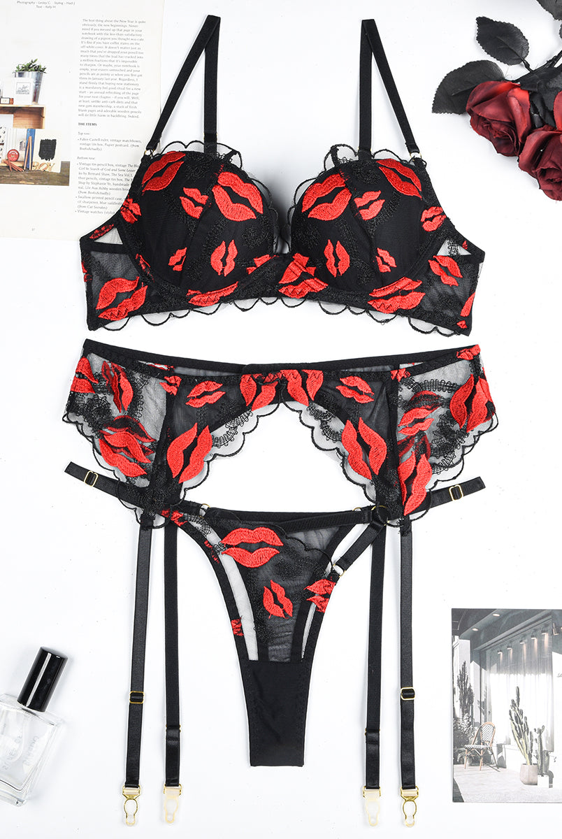 Black lace lingerie set with red lip embroidery. Bra, garter belt, and thong. Sensual design.