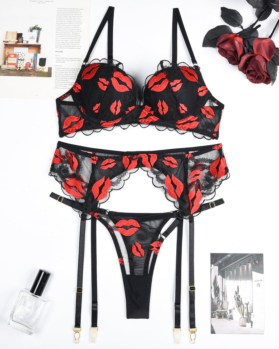 Black lace lingerie set with red lip embroidery. Bra, garter belt, and thong. Sensual design.