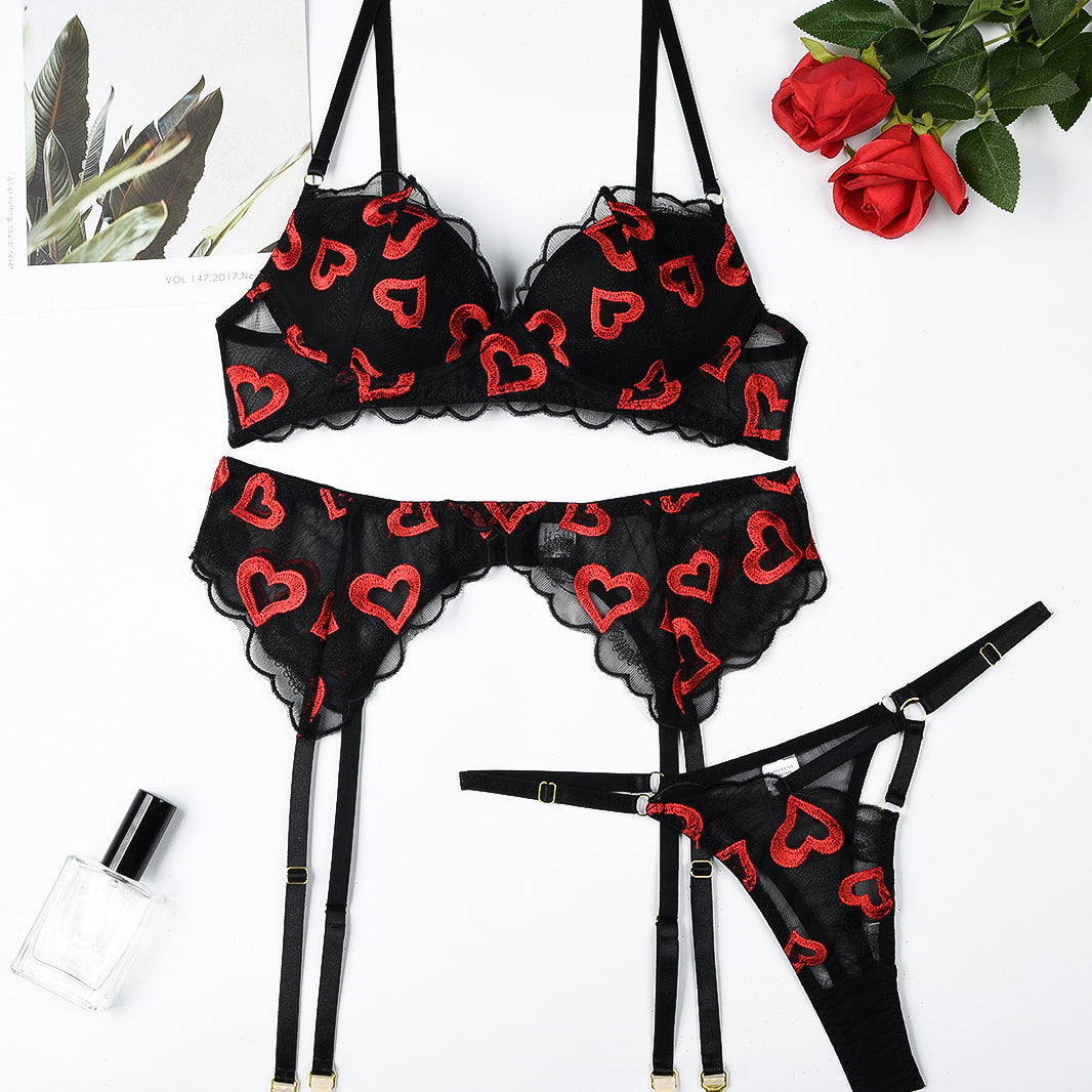 Black lace lingerie set with red heart embroidery; bra, garter belt, and thong.