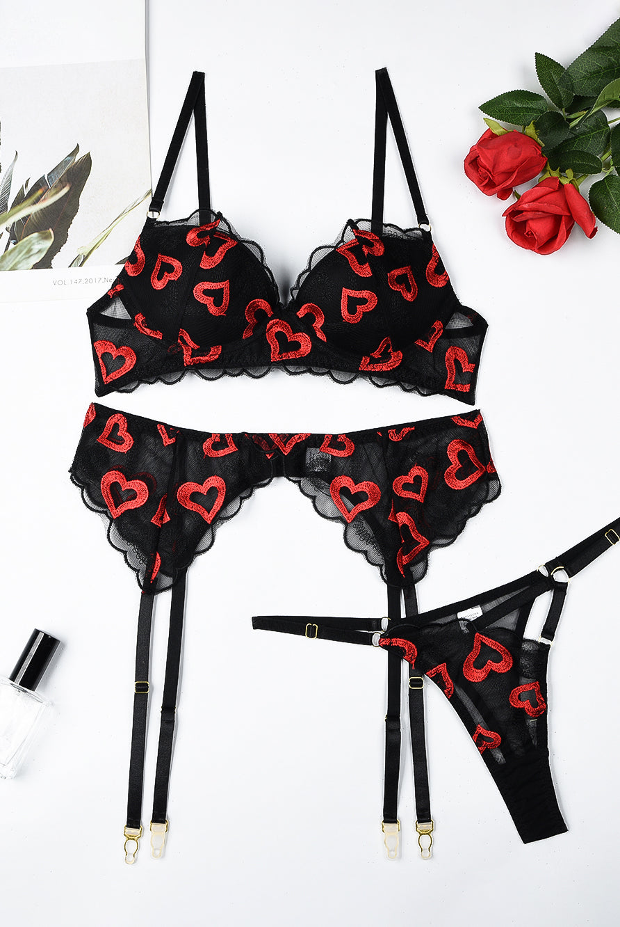 Black lace lingerie set with red heart embroidery; bra, garter belt, and thong.