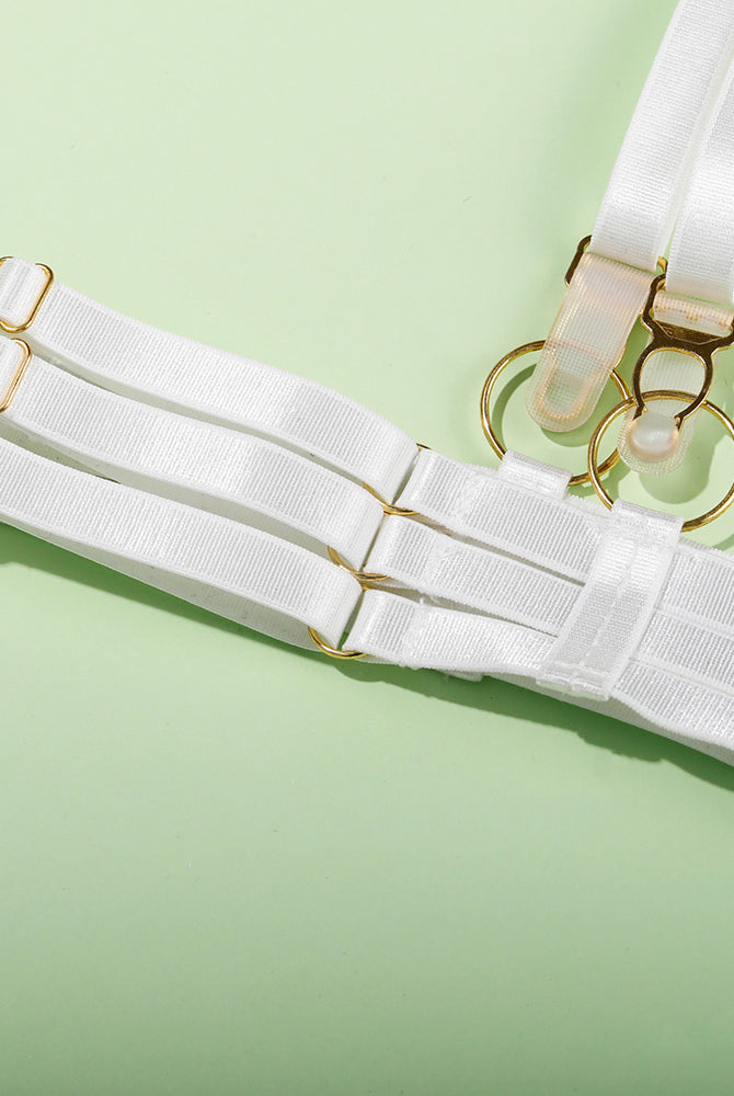 White lingerie set with adjustable straps and gold hardware, delicate and seductive.