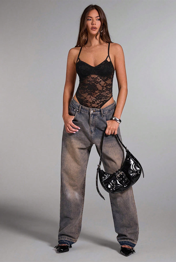 Black floral lace bodysuit on a model, sheer design, denim jeans, and black handbag