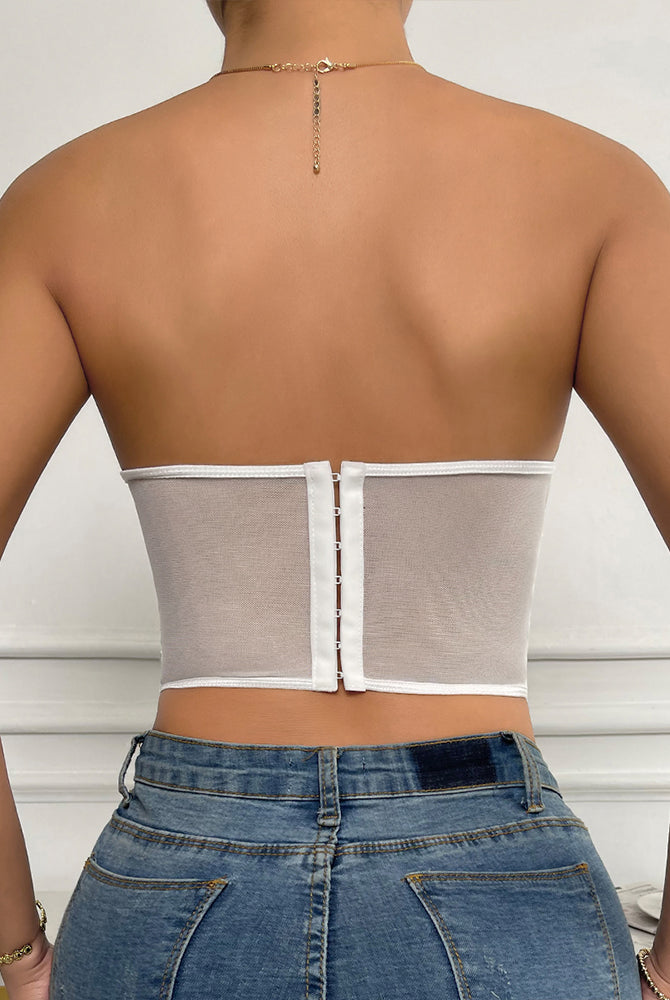 White strapless mesh bustier top with boning, offering support and shaping, paired with denim jeans.