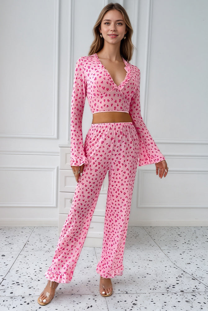 Pink heart print pajama set with ruffled top and pants, perfect for comfortable sleepwear.
