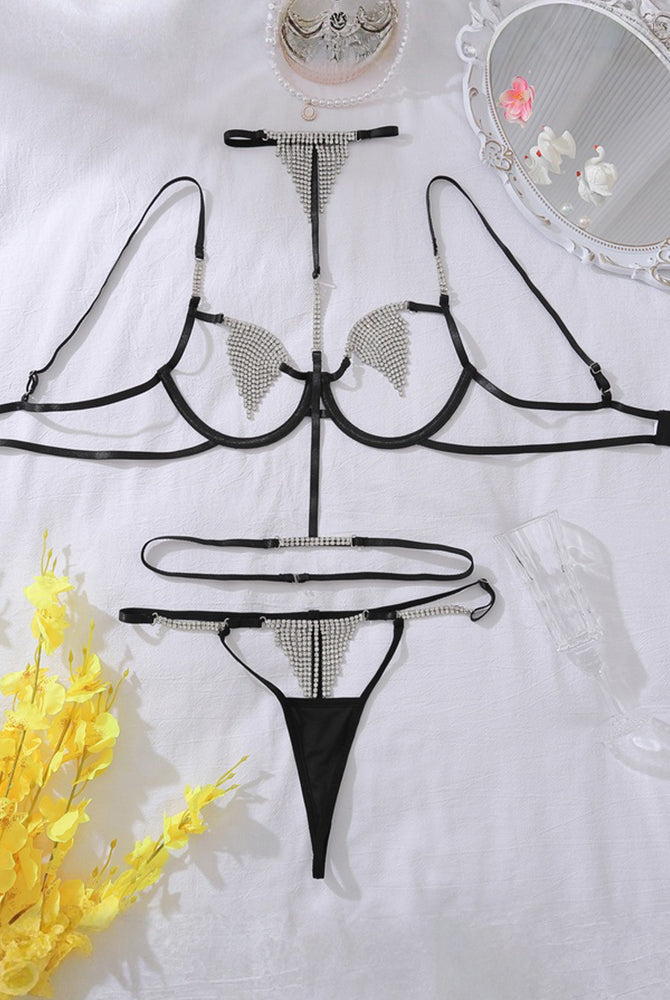 Black diamond-studded lingerie set laid flat: bra, thong, and halter straps