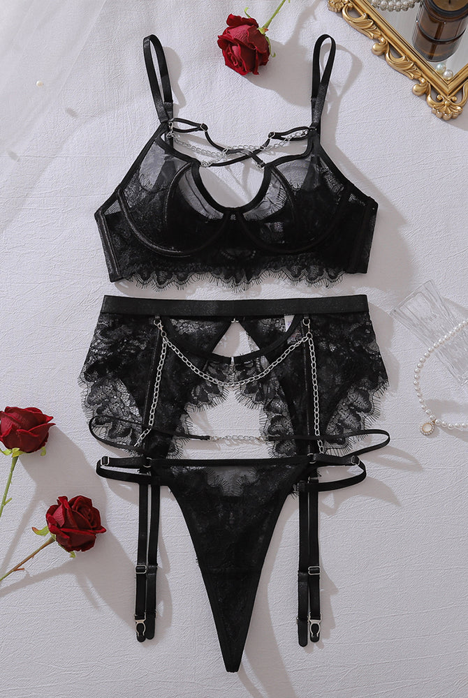 Black sheer mesh lingerie set flat lay: bra, lace harness briefs, garters, chain