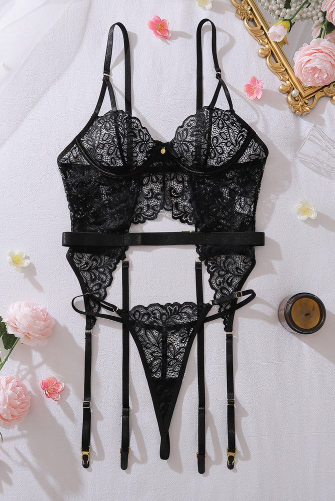 Black lace lingerie set laid flat: bra, thong, garter belt and adjustable straps