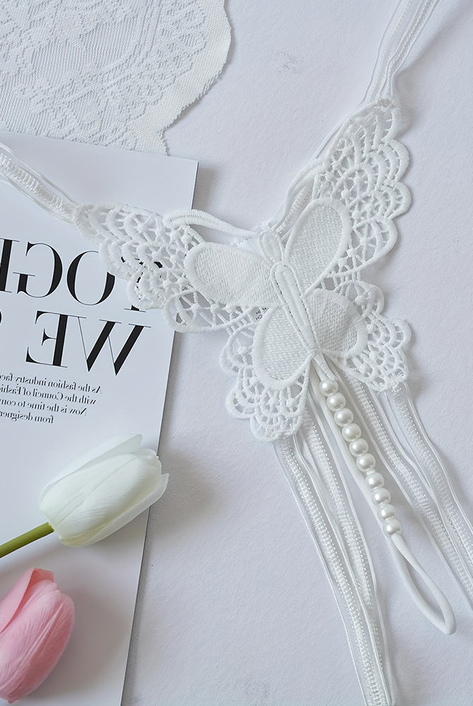 White lace thong panties flat lay with butterfly applique and pearl tassel trim
