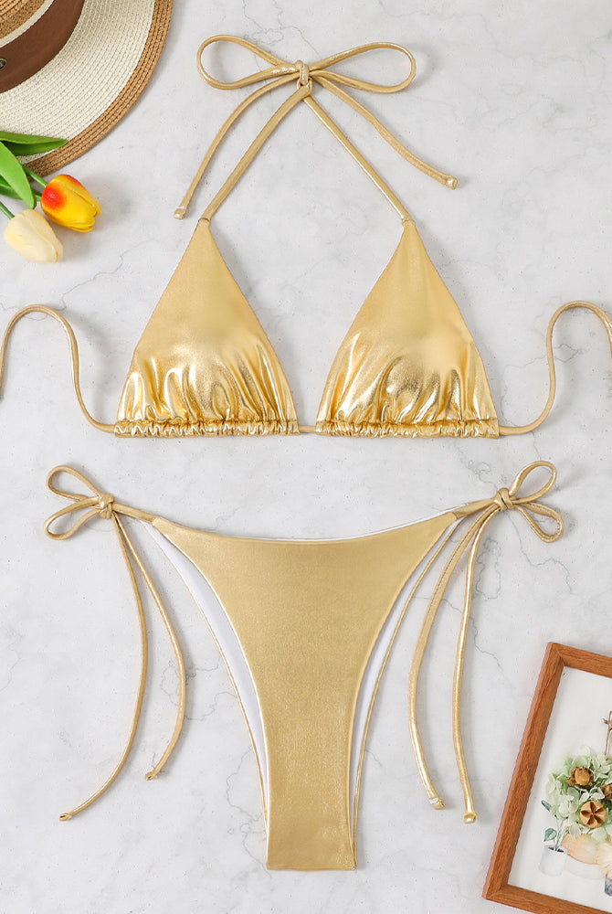 Gold shiny metallic triangle halter bikini top and matching side-tie thong bottoms, laid flat