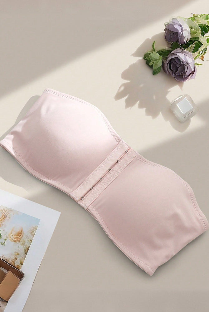Strapless bandeau bra in blush pink, flat lay showing smooth cups and front hook closure