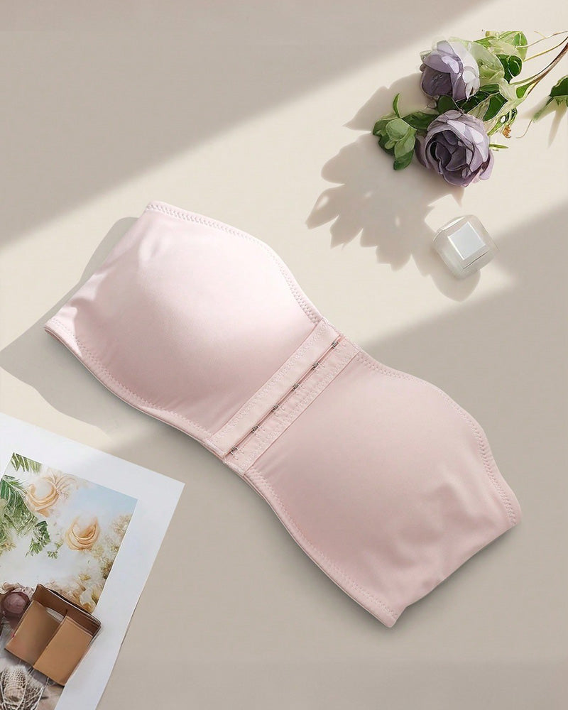Strapless bandeau bra in blush pink, flat lay showing smooth cups and front hook closure