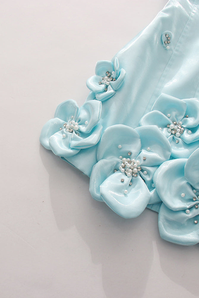 Close-up of sky blue 3D floral rosette appliques with rhinestone and pearl details.