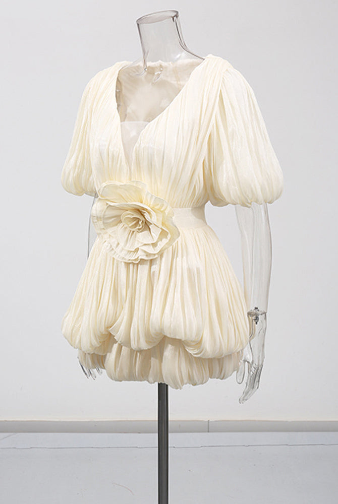 Champagne mini dress on mannequin with deep V, pleated puff sleeves, floral waist detail