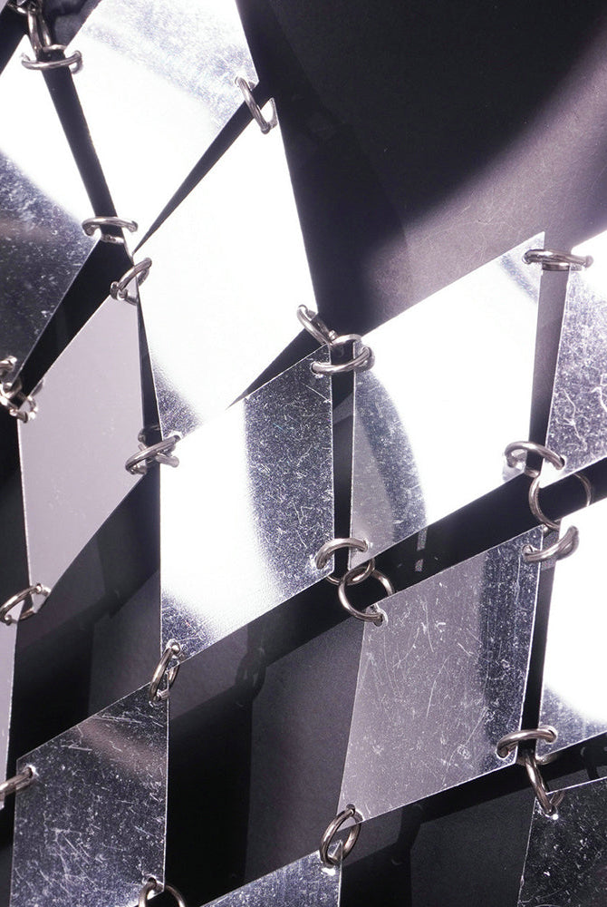 Close-up of silver metal chain-link pattern on a dark backing panel.